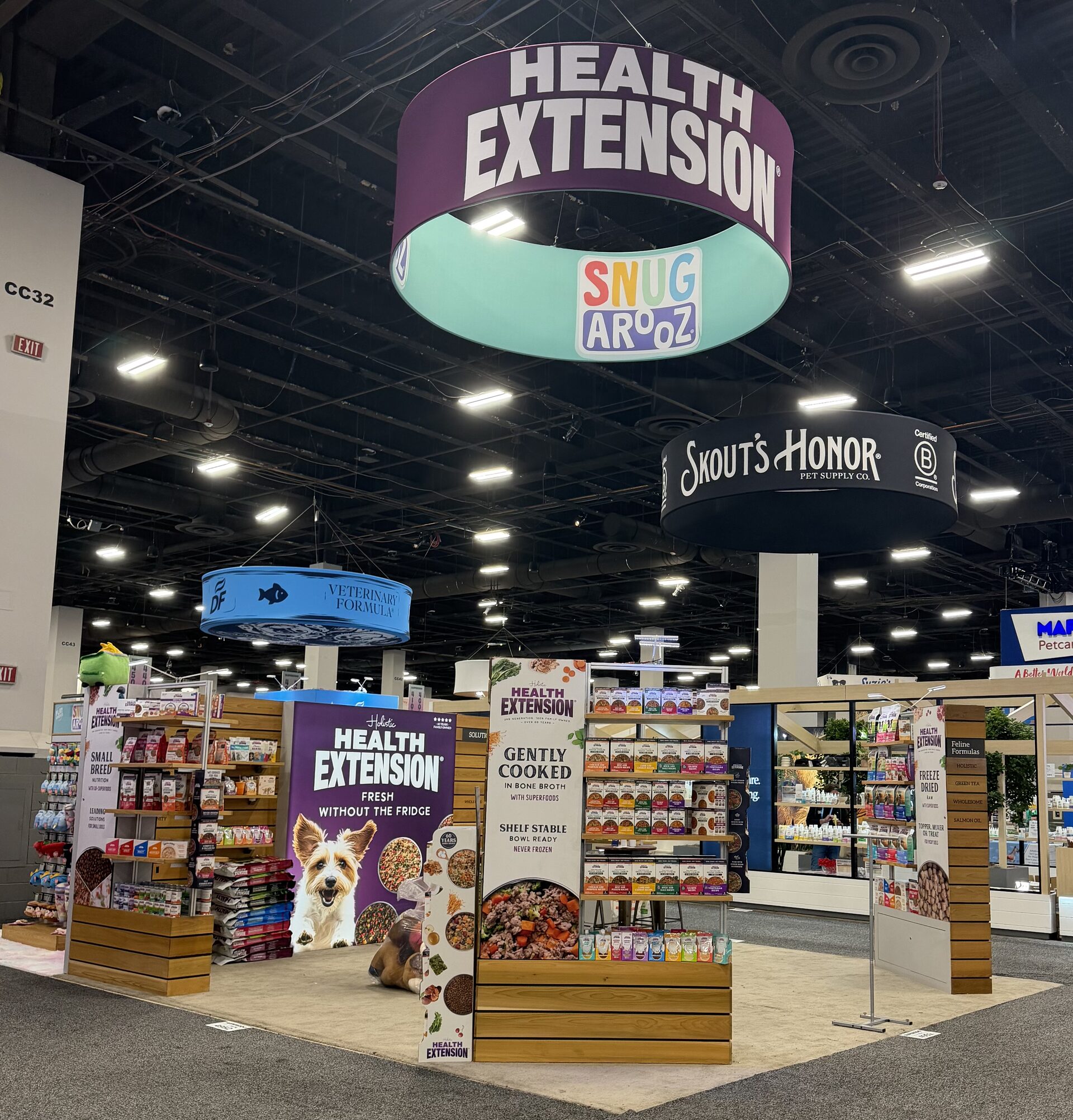 Trade-show booth with large suspended circular banner signs over modular shelving displays on the show floor