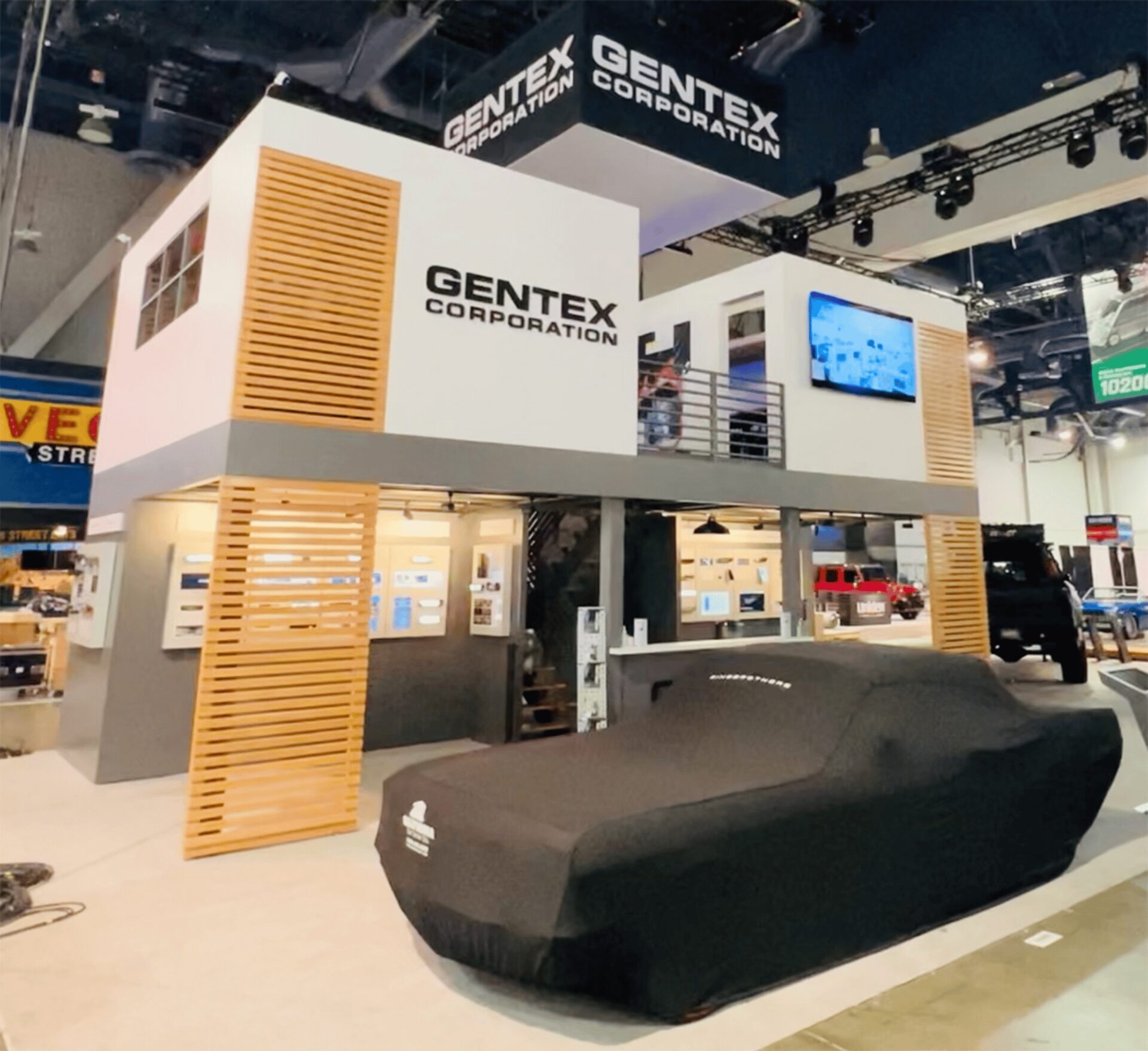 Two-story trade-show exhibit with an upper mezzanine deck and slatted wood towers on a convention-hall floor